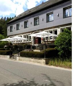 ein Gebäude mit Tischen und Sonnenschirmen davor in der Unterkunft Hotel L'ermitage in Houffalize