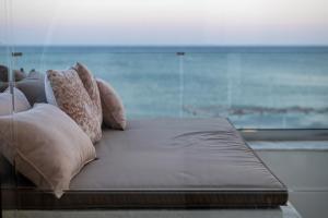 a bed with pillows and a view of the ocean at Porto Lygia Apartment in Ierápetra