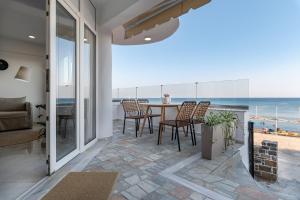uma sala de estar com mesa e cadeiras e o oceano em Porto Lygia Apartment em Lerápetra