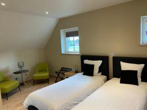 a bedroom with two beds and a green chair at B&B 't Mjeels Pierke in Meerle