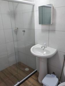 a bathroom with a sink and a glass shower at Pousada e Hotel Malibu in Paulista