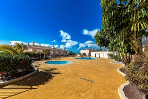 two pools in a courtyard with trees and buildings at Spacious Ocean View Family Townhouse in Puerto de Santiago
