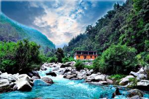 a river with a house in the middle of a mountain at Kareri River Bliss in Dharamshala