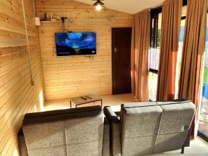 ein Wohnzimmer mit einem Sofa und einem TV an der Wand in der Unterkunft House&Yard Hellen 150m to beach in Ureki