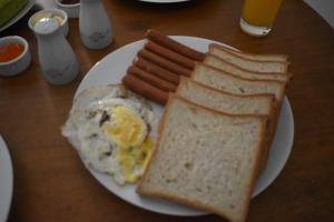 a white plate with eggs sausage and toast on a table at Orchard Home in Kandy