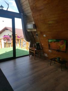 a living room with a wooden floor and a large window at Cabana Ema in Curtea de Argeş