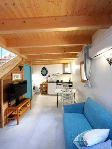 uma sala de estar com um sofá azul e uma cozinha em La Grange aux hirondelles em Laroque-des-Albères