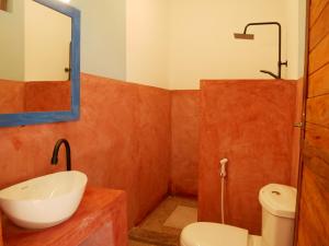 a bathroom with a sink and a toilet and a mirror at Sabali Lodge, Zanzibar in Jambiani