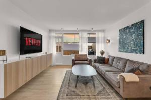 ein Wohnzimmer mit einem Sofa und einem TV in der Unterkunft Venture Vacation-Family Friendly Retreat-HOT TUB in Mosfellsbær