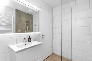 Baño blanco con lavabo y espejo en Venture Vacation-Family Friendly Retreat-HOT TUB, en Mosfellsbær