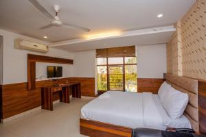 Hotel DOON في دهرادون: غرفة نوم بسرير ومكتب وتلفزيون