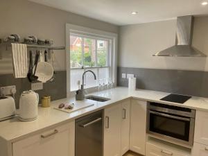 a kitchen with white cabinets and a sink and a window at The Greig 1A in Wadhurst