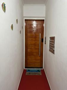 a hallway with a wooden door and a red floor at Apartamento frente ao mar com varanda e piscina in Praia Grande