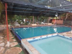 a large swimming pool with an umbrella over it at New Sunrise Hotel in Batticaloa