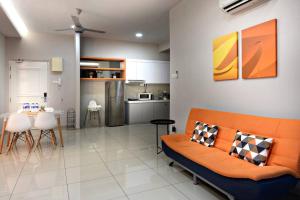 a living room with an orange couch and a kitchen at InStay Atlantis - The Orange in Melaka