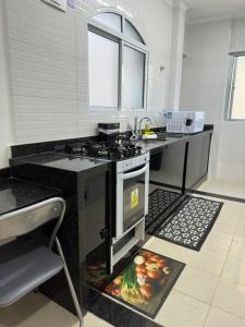 a kitchen with a stove and a counter top at Apartamento frente ao mar com varanda e piscina in Praia Grande