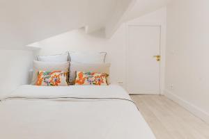 een witte slaapkamer met een wit bed met kussens bij Magnifique maisonnette sur cour intérieur proche des quais de la seine in Parijs