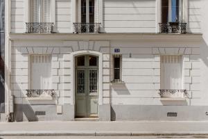 een wit gebouw met een groene deur in een straat bij Magnifique maisonnette sur cour intérieur proche des quais de la seine in Parijs