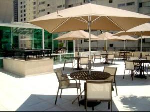 un patio al aire libre con mesas, sillas y sombrillas en Upper Hotel, en São Paulo