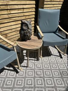 a statue of an owl sitting on a table next to two chairs at Sèid Bò - Sleeps 6 - NEW Private 6 Person HotTub Available in Burnfoot
