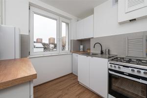 a kitchen with white cabinets and a large window at Apartament Octopus Sopot Kamienny Potok in Sopot