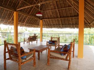 un porche con sillas, una mesa y una persona en Sabali Lodge, Zanzibar, en Jambiani