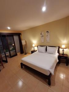 a bedroom with a large white bed and two lamps at Dalia Budget Hotel in Senggigi