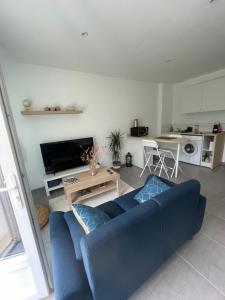 a living room with a blue couch and a kitchen at Studio meuble Kenaya 29m2. in Saint-Étienne-du-Rouvray