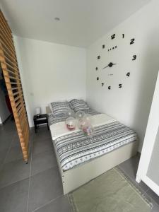 uma cama num quarto com um relógio na parede em Studio meuble Kenaya 29m2. em Saint-Étienne-du-Rouvray