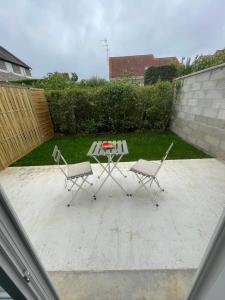 een patio met 2 stoelen en een tafel in de tuin bij Studio meuble Kenaya 29m2. in Saint-Étienne-du-Rouvray