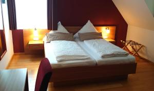 um quarto com uma cama com lençóis brancos e almofadas em Bräustüble Altenmünster em Altenmünster