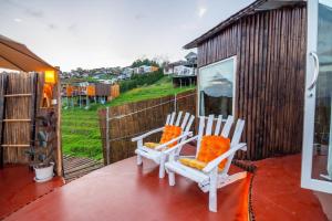 2 chaises blanches assises sur une terrasse avec une maison dans l'établissement เดอะเนเจอร์ ม่อนแจ่ม The nature camping monjam, à Mon Jam