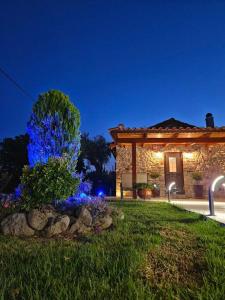 une maison en pierre avec des lumières bleues dans une cour dans l'établissement Patras stonehouse with large yard - Πέτρινο σπίτι με αυλή, à Paralía