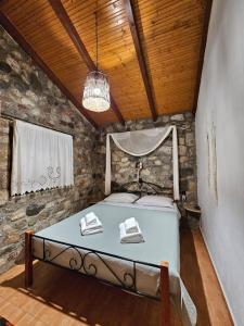 - une chambre avec un lit dans un mur en pierre dans l'établissement Patras stonehouse with large yard - Πέτρινο σπίτι με αυλή, à Paralía