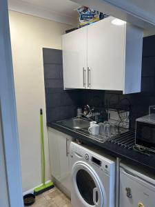 a kitchen with a washing machine and a sink at Jah lodge in Croydon