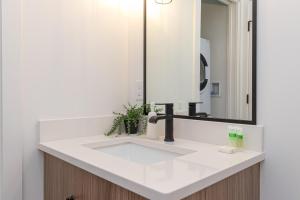 a bathroom with a white sink and a mirror at Be Close To Chinatown When You Are In The Ironwork Building in Victoria +30 photos