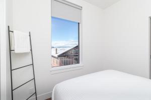 ein weißes Schlafzimmer mit einem Fenster und einem Bett in der Unterkunft Ironworks Building Victoria in Victoria
