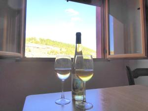 two wine glasses sitting on a table with a bottle of wine at Casa rural Butaka in Alcalá del Júcar