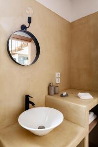 Monopati Eco Villas في Raches: حمام مع حوض أبيض ومرآة