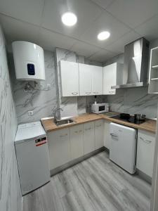 una cucina bianca con armadietti e elettrodomestici bianchi di Green Suite ad Albacete