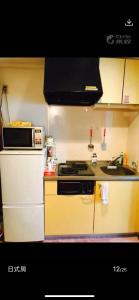 uma cozinha com um fogão e um micro-ondas em 新宿の家-畳み3人部屋 em Tóquio