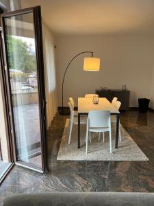 a dining room table with white chairs and a glass door at Casa Parisi Lago Maggiore in Baveno