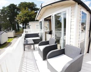een veranda met stoelen en tafels in een huis bij Sea Breeze Cabin in Poole