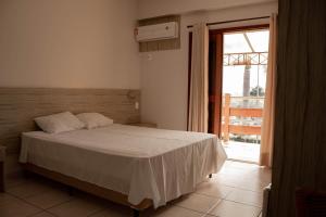 1 dormitorio con cama y ventana grande en Hotel Thermas Bonsucesso, en Jataí