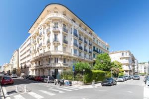 Un gran edificio blanco con coches aparcados delante. en FEEL HOME - FOCH 28, en Niza