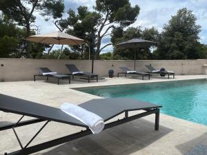 una piscina con sedie a sdraio e ombrelloni accanto ad essa di Villa Salteria 3, pool, private territory, pinery a Rovigno (Rovinj)