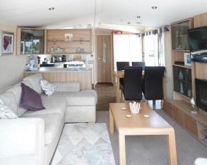 sala de estar con sofá y mesa en Sea Breeze Cabin, en Poole