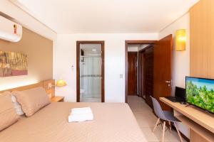 a bedroom with a bed and a desk with a television at [KaririBeach319B] Suíte com vista incrível in Cumbuco