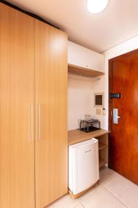 - une cuisine avec des placards en bois et un réfrigérateur blanc dans l'établissement Linda Suíte em Apart-hotel com vista incrível!!!, à Cumbuco