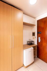 a kitchen with wooden cabinets and a white refrigerator at [KaririBeach319B] Suíte com vista incrível in Cumbuco